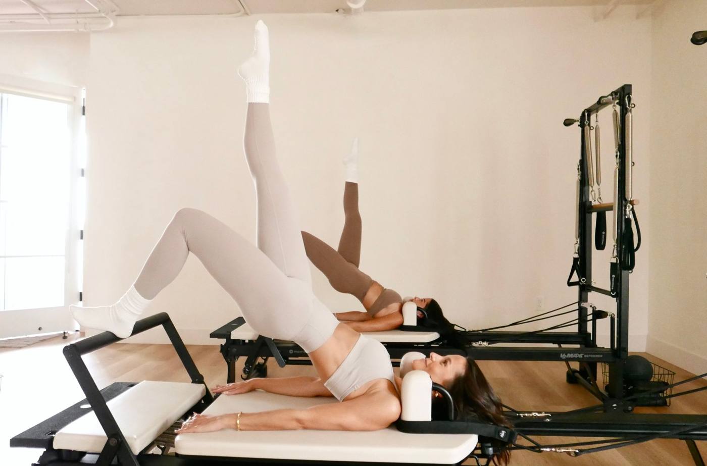 Woman doing a leg exercise on the reformer with the tower attached